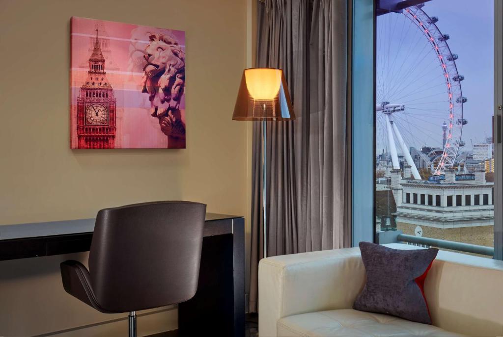 a hotel room with a chair and a desk and a large window at Park Plaza London Westminster Bridge in London