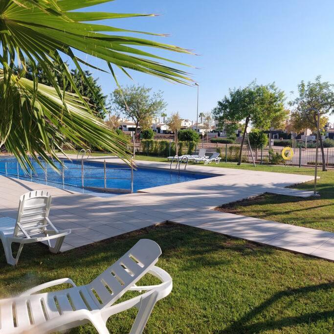 twee witte ligstoelen naast een zwembad bij Un Oasis en Hacienda del Álamo in Murcia