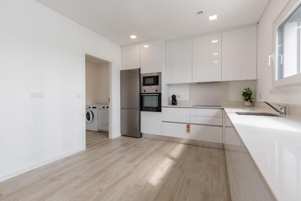a white kitchen with white cabinets and a wooden floor at Villa Patricia in Santa Barbara