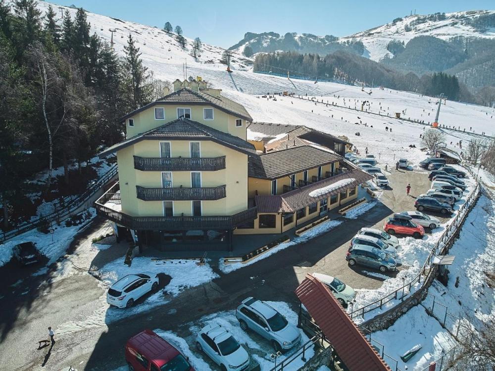 a large building with cars parked in a parking lot at Hotel Dolomiti in Brentonico