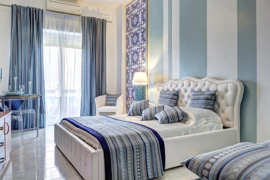 a bedroom with a large white bed with blue walls at SuiteHome Taormina in Giardini Naxos