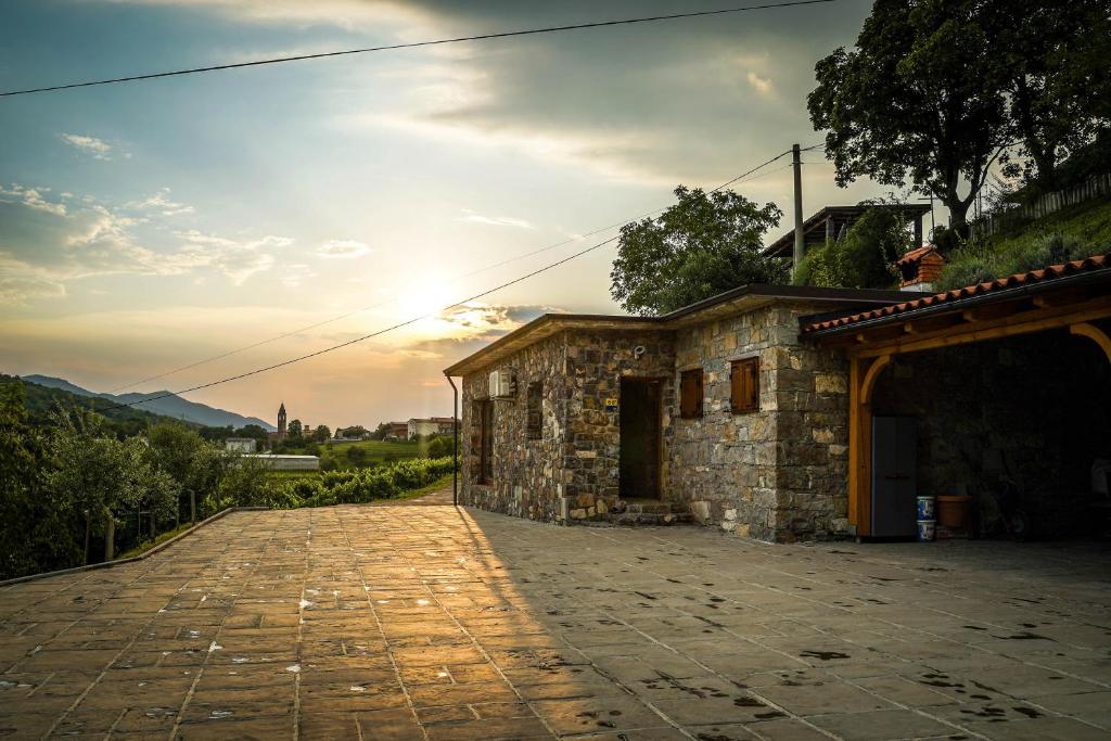 un edificio de piedra con la puesta de sol en el fondo en Holiday Home GaMaJaMa en Dobravlje