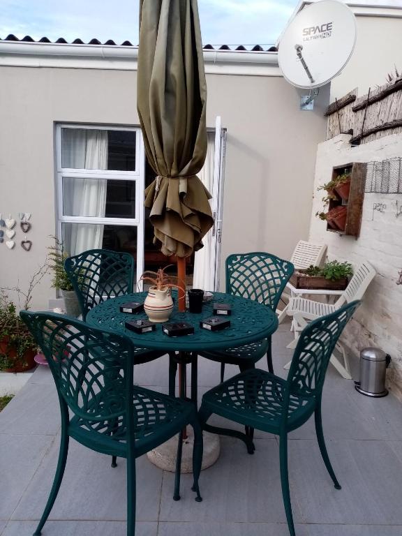 a patio table with four chairs and a umbrella at Lor's Place in Mount Road