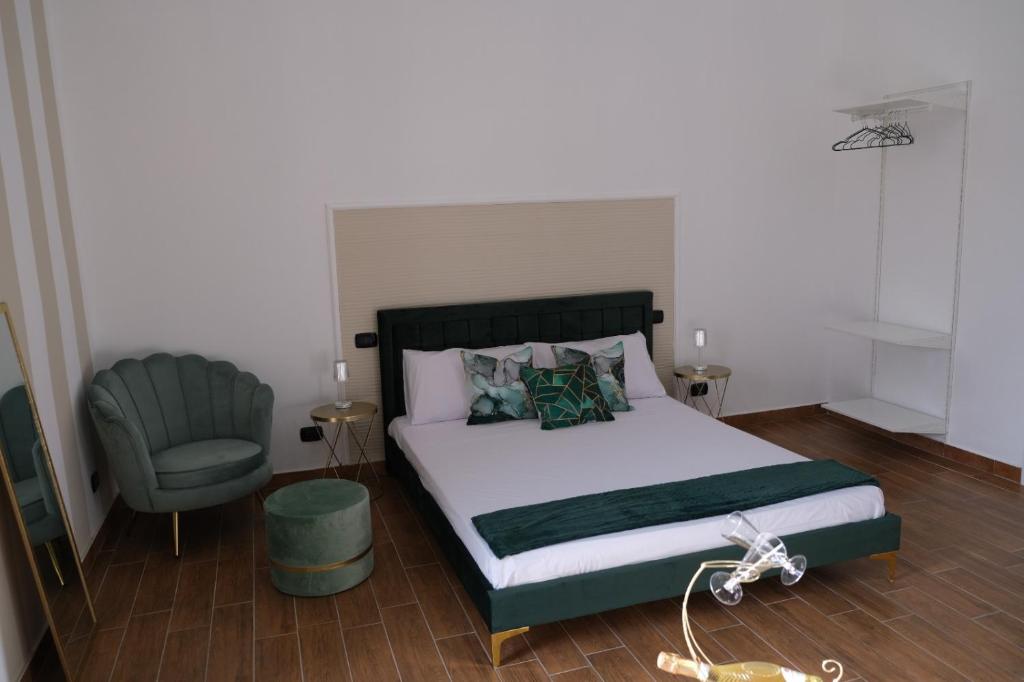 ein Schlafzimmer mit einem Bett und einem grünen Stuhl in der Unterkunft SUITE LA VILLA in Statte