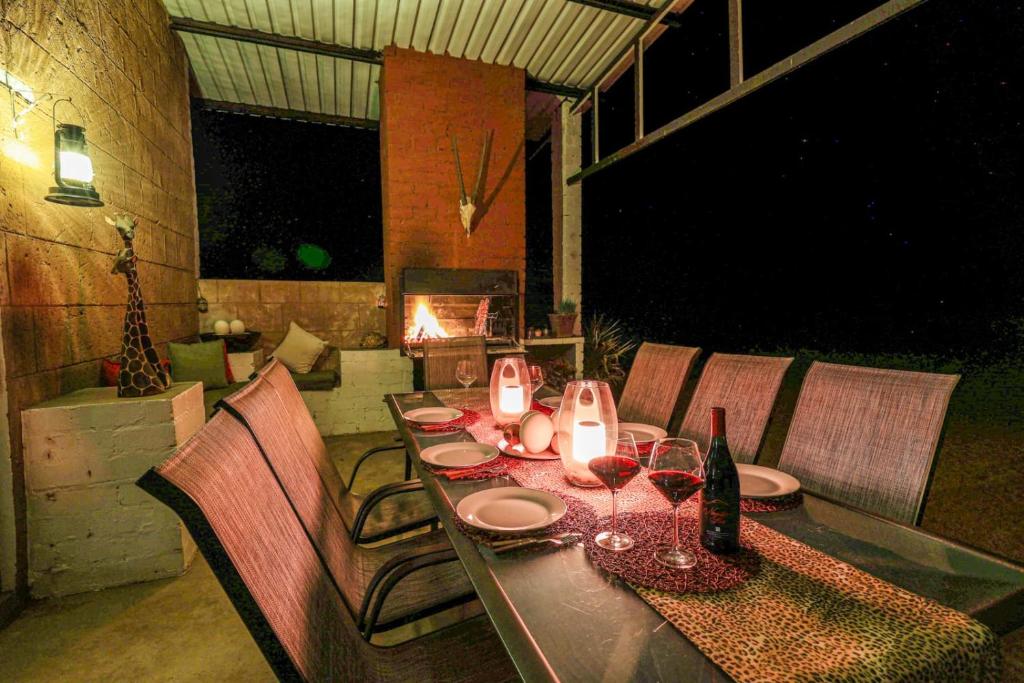 a dining table with wine glasses and a fireplace at Big Cats Namibia Self Catering Farm Guesthouse in Outjo