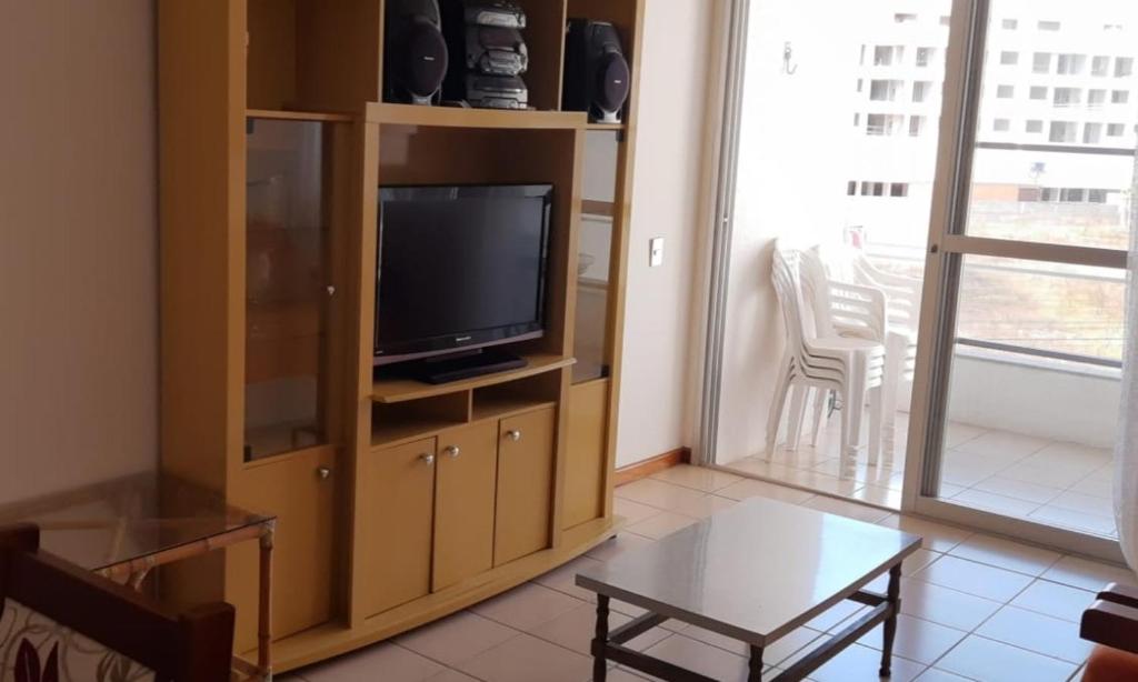 uma sala de estar com uma televisão e uma mesa em Apto dois quartos pertinho da praia em Florianópolis