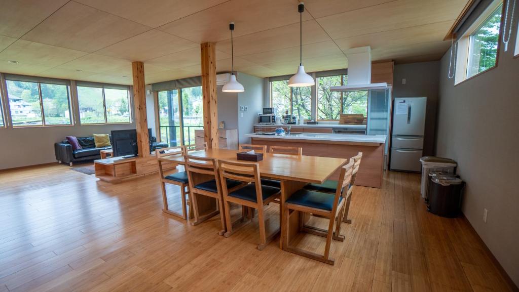 uma cozinha e sala de estar com uma mesa de madeira e cadeiras em Serenity Chalet, walk to the lifts Happoone Ski Resort em Hakuba