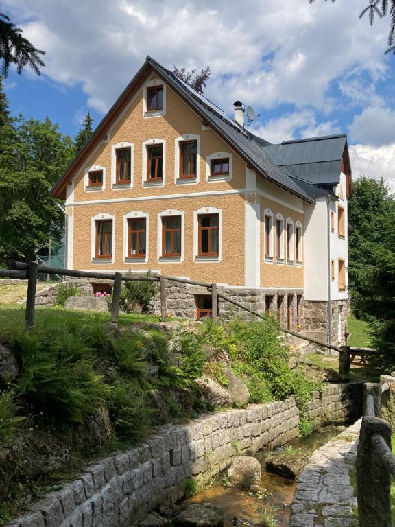 a large house with a stone wall next to a river at Tichá říčka in Josefŭv Dŭl