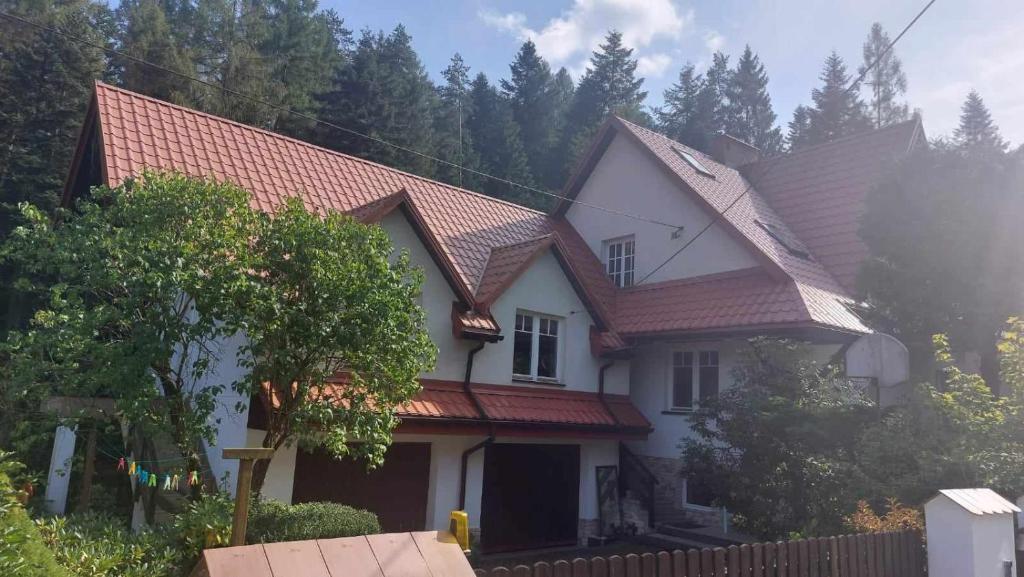 Casa blanca con techo rojo en Beskidzka Apartments, en Sucha Beskidzka
