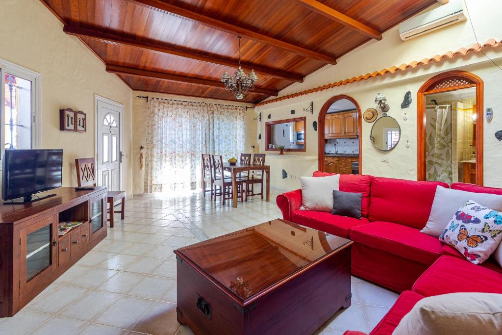 a living room with a red couch and a tv at Casa cueva El Balcón del Cortijo in Teror
