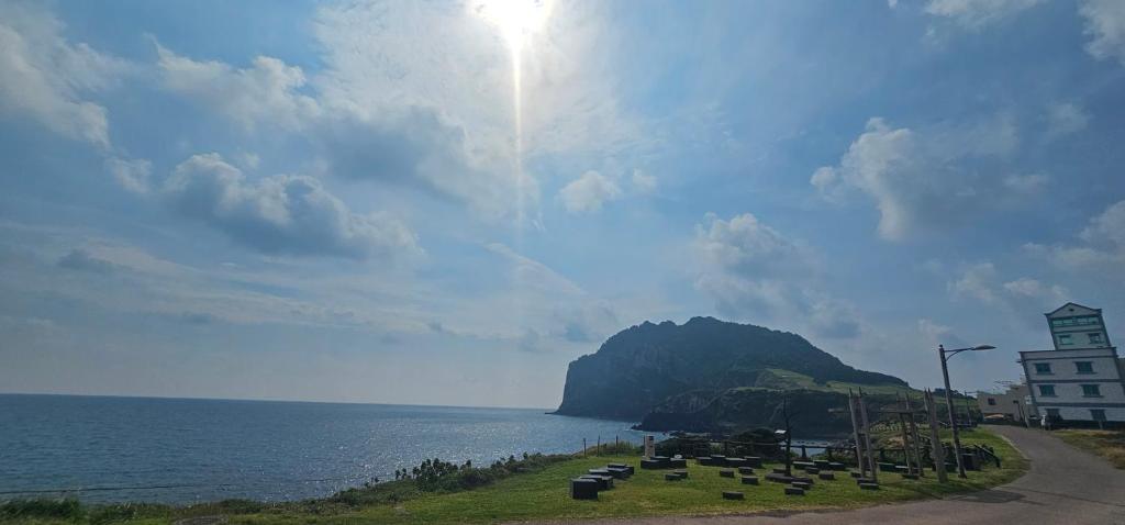 a road next to a body of water with a mountain at Seongsan Morning Sunset in Seogwipo