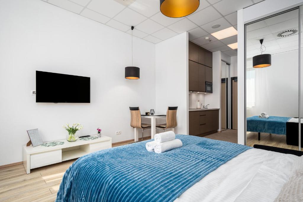 a bedroom with a blue and white bed and a kitchen at Al Jerozolimskie 216 APART-WAWA in Warsaw