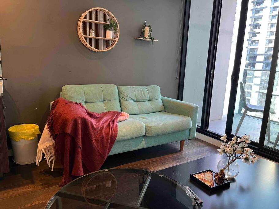 a living room with a green couch and a table at City-view High Rise 2BR Apt w/Pool, Sauna Gym, Library near Southern Cross Station Melbourne CBD in Melbourne