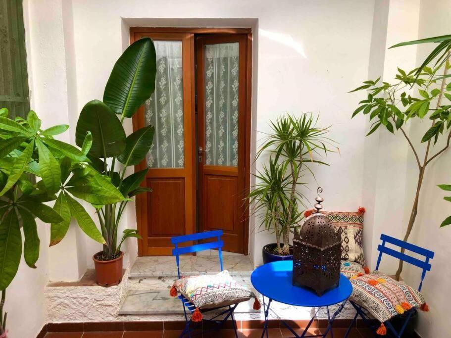 a patio with a table and two blue chairs and a door at Via della Campana 17 in Portoferraio