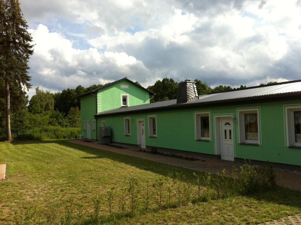 ein grünes Haus mit einem Hof davor in der Unterkunft Ferienwohnung am Heegesee in Wesenberg