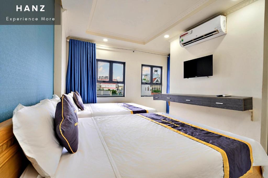 HANZ Minh Thu Hotel Tan Binh في مدينة هوشي منه: غرفة نوم بسريرين وتلفزيون على الحائط