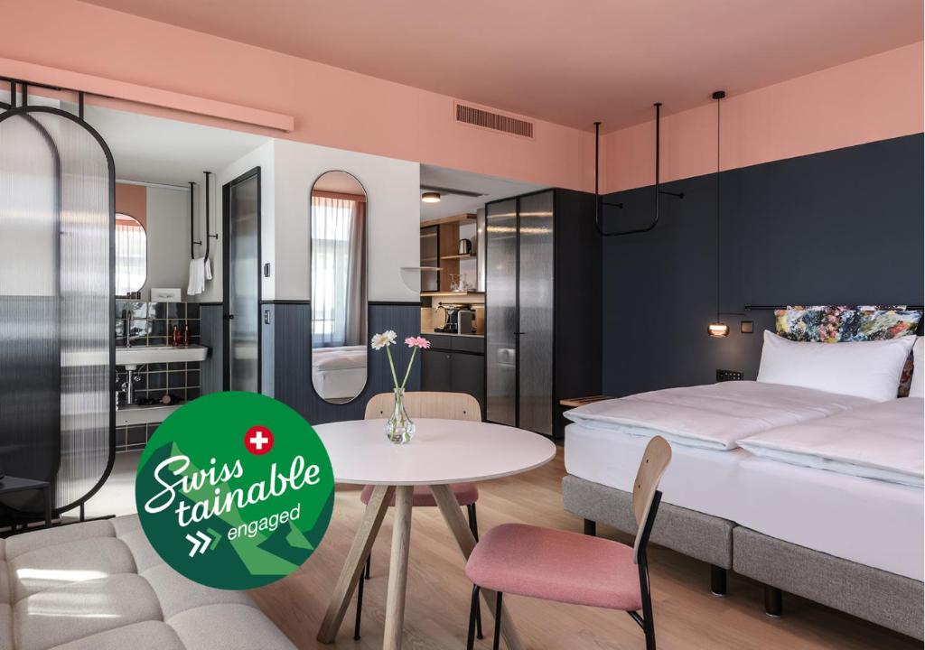 a bedroom with a bed and a table and a kitchen at Sorell Hotel City Weissenstein - Boutique Hotel in St. Gallen