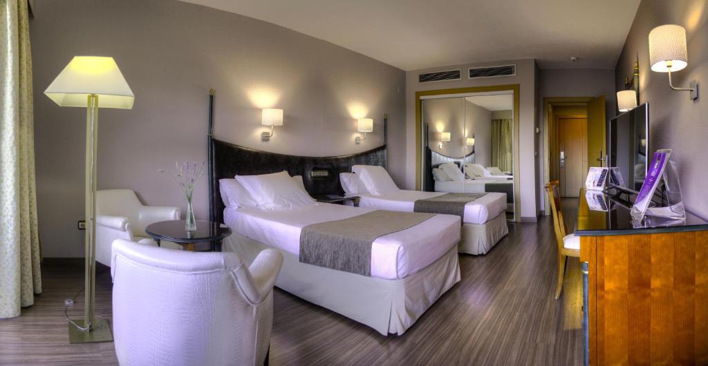 a hotel room with two beds and a television at Beatriz Toledo Auditorium & Spa in Toledo