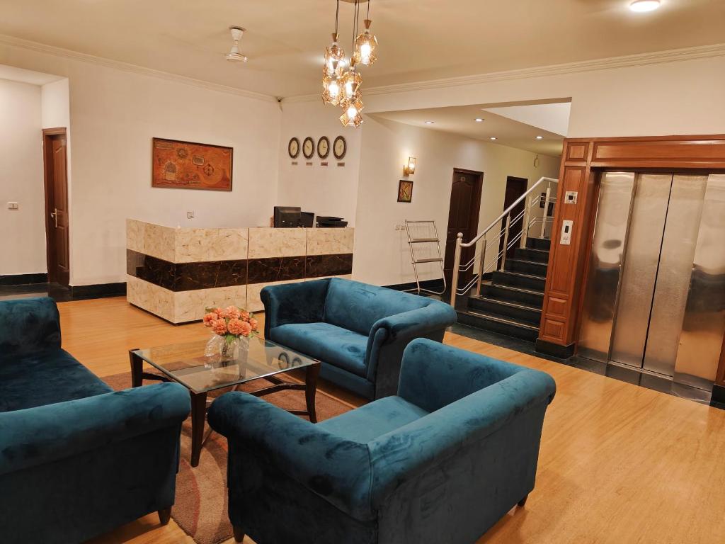a living room with blue couches and a table at Hotel Amisa Golf Course Road MG Road in Gurgaon