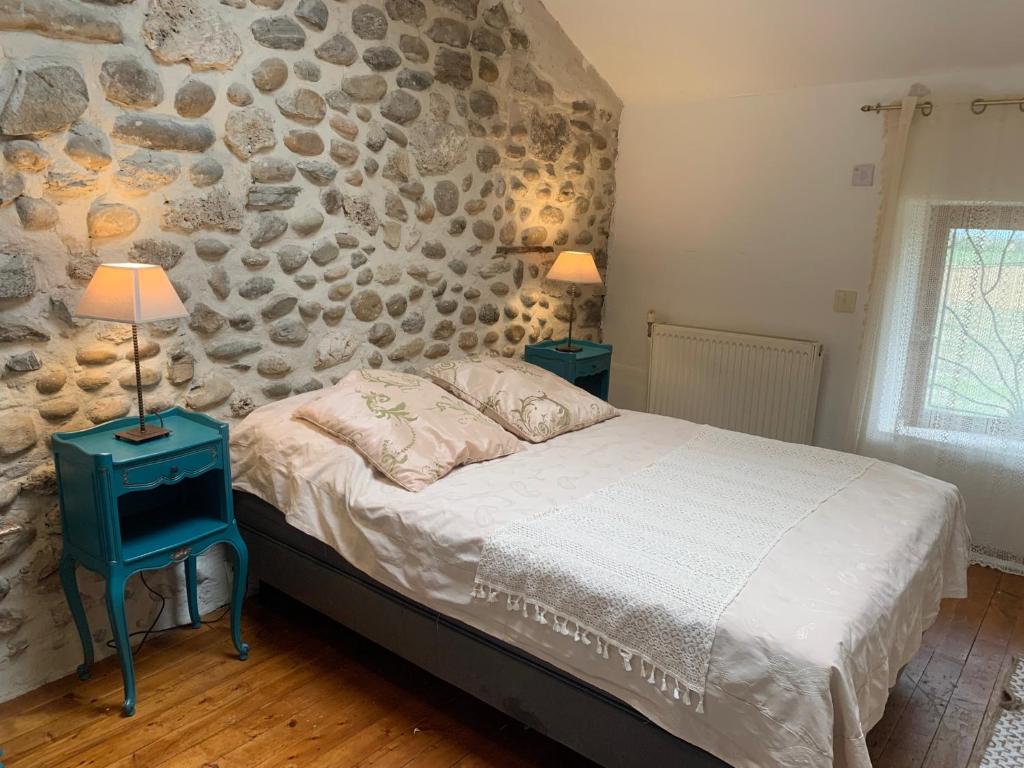 a bedroom with a bed and a stone wall at Vercors en Vert , chambres d'hôtes de charme in Saint-Romans