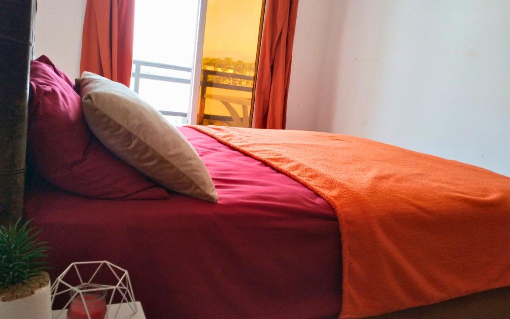 Una cama con una manta naranja encima. en Rouge Plage Studio, en Agadir