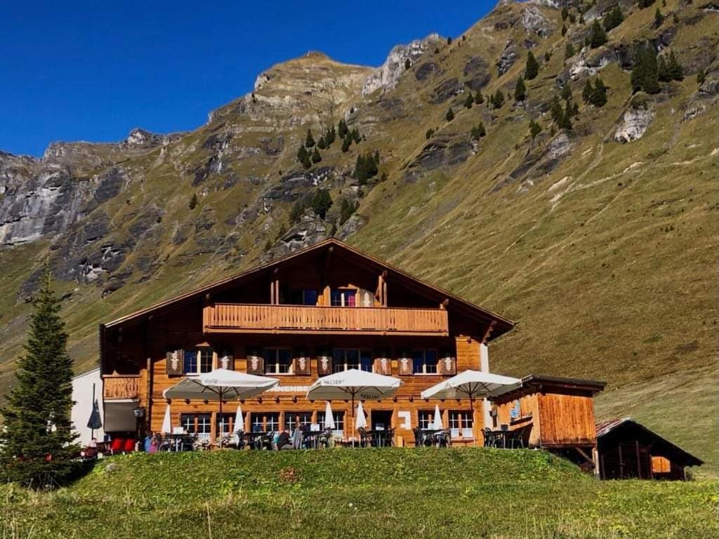 a large building on a hill in front of a mountain at Sonnenberg Dormitories in Mürren