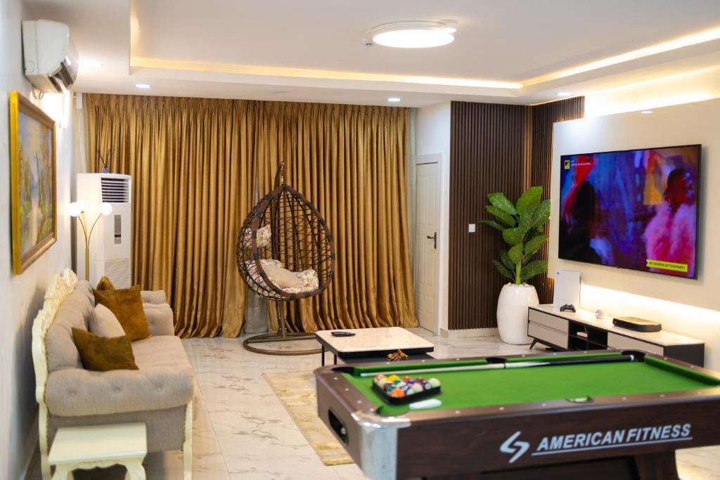 Gerdette Luxury Apartment في لاغوس: غرفة معيشة مع طاولة بلياردو وتلفزيون