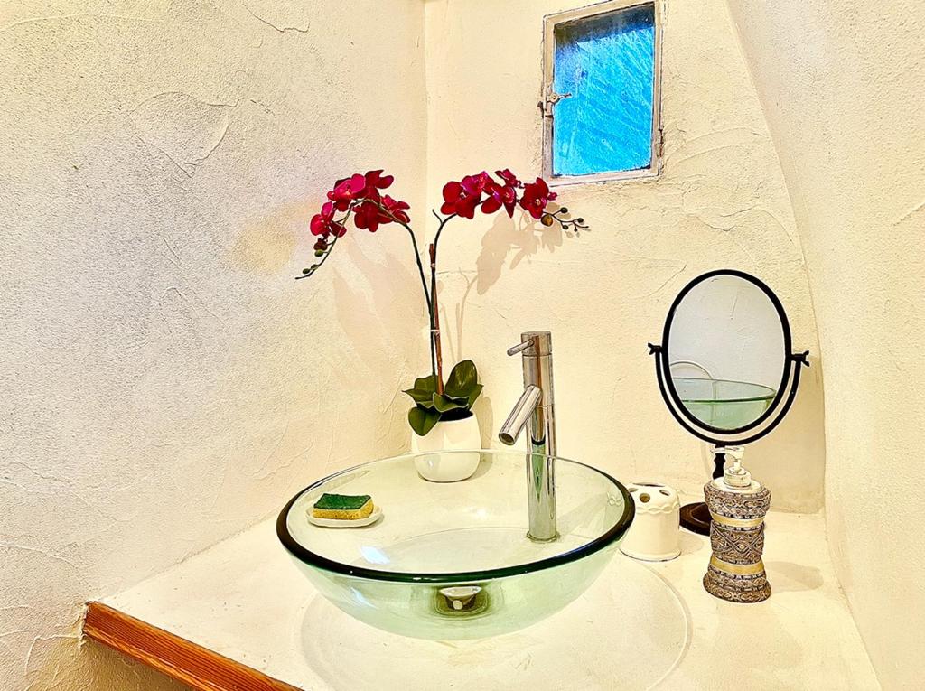 a bathroom sink with a mirror and a vase with flowers at Caporizon-Sarlat l&#39;élégance-T2 Plein centre cité médiévale in Sarlat-la-Canéda