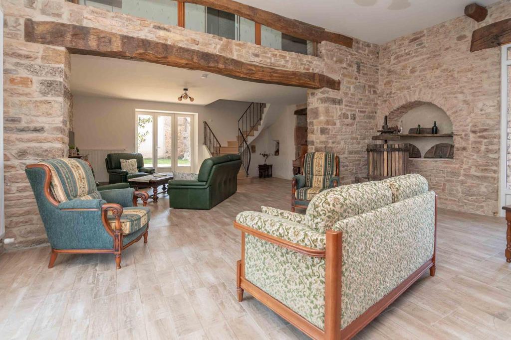 a living room with two couches and a brick wall at Le Grand Pressoir - Grande maison avec jardin in Nanton