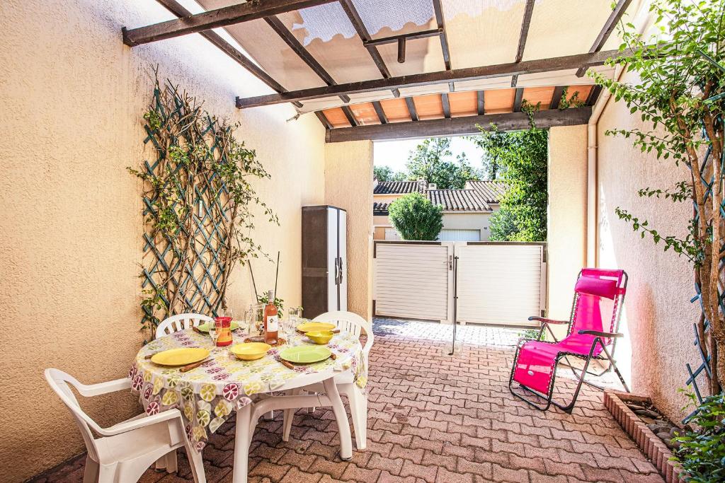 d'une terrasse avec une table, des chaises et une porte ouverte. dans l'établissement Maisonnette du Clos - Avec piscine partagée, à Argelès-sur-Mer