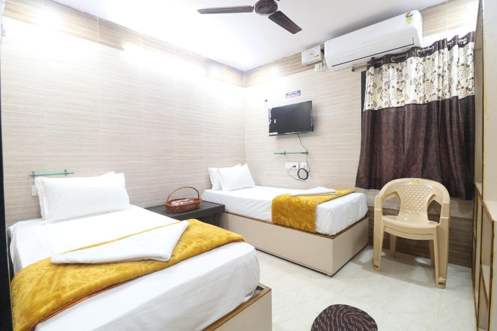 a hotel room with two beds and a tv at HOTEL VALLABHA RESIDENSY in Rājahmundry