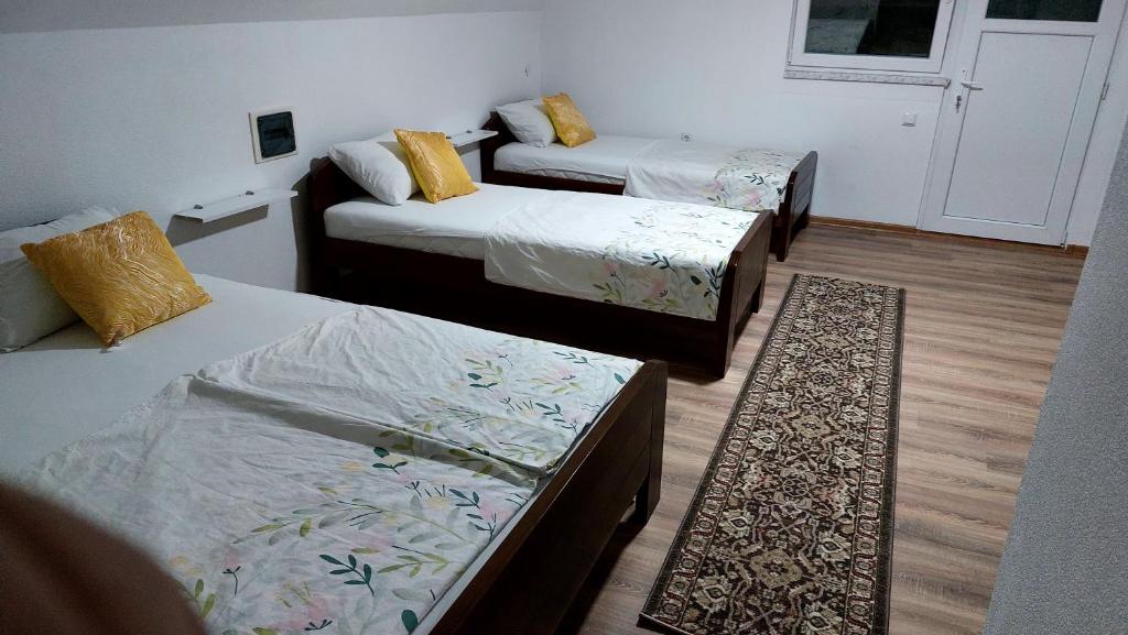 Habitación con 3 camas y alfombra. en Amar Apartmani,,, en Živinice