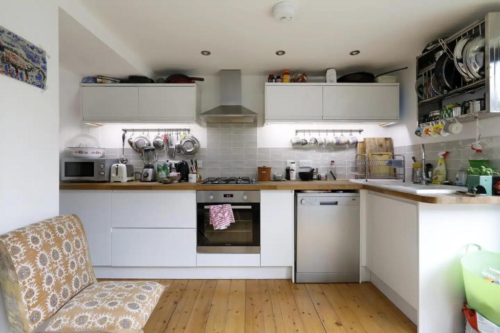 a kitchen with white cabinets and a chair in it at Three Bedroomed Victorian Family House, Garden in Brighton & Hove