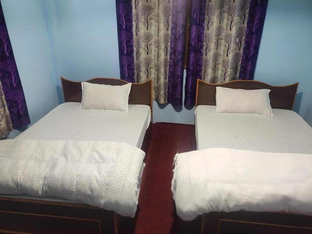 two twin beds in a room with purple curtains at Hotel Swornim Namobuddha in Dhulikhel