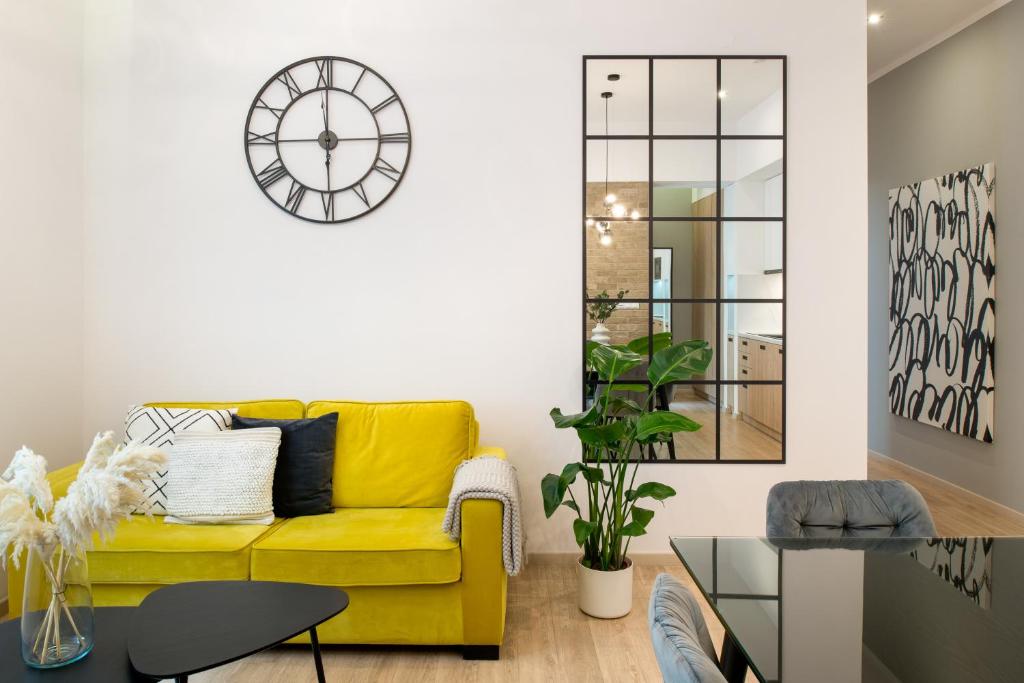 クラクフにあるBeautiful Apartment with 2 bedrooms for 7 guests, Jewish Districtの壁掛け時計付きのリビングルーム(黄色のソファ付)