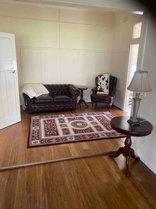 a living room with couches and a table and a rug at Golden Street Cottage in West Wyalong