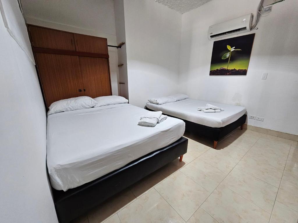 2 łóżka w małym pokoju z białymi ścianami w obiekcie Apartamento En La Circunvalar Por Parceros Group w mieście Pereira