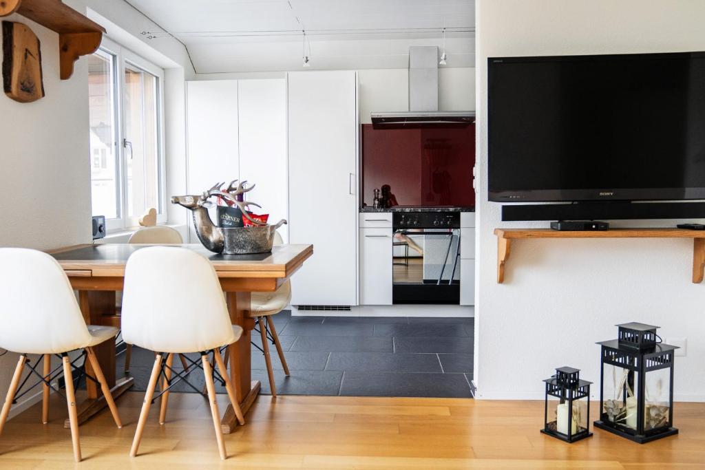 a kitchen with white cabinets and a table with white chairs at GLARNER Bed in Netstal