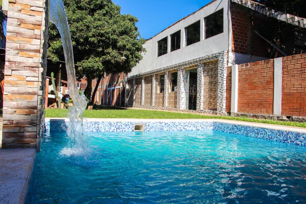 a pool with a fountain in front of a building at Ullanka Apart Hotel in Encarnación