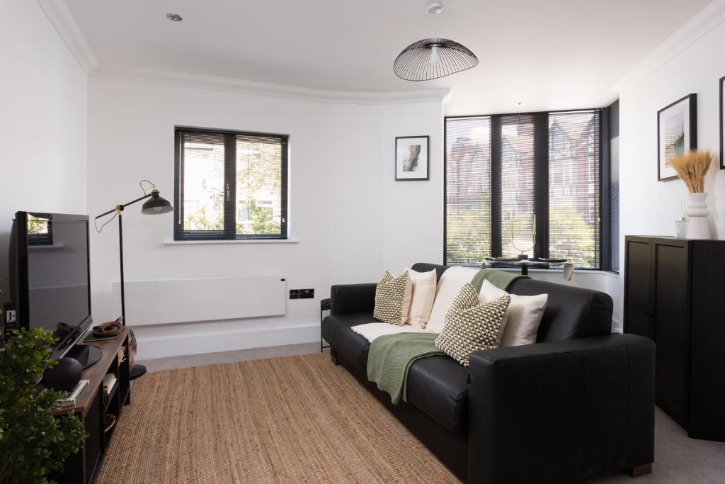 a living room with a black couch and windows at London Mews, modern apartment - sleeps 4 in York