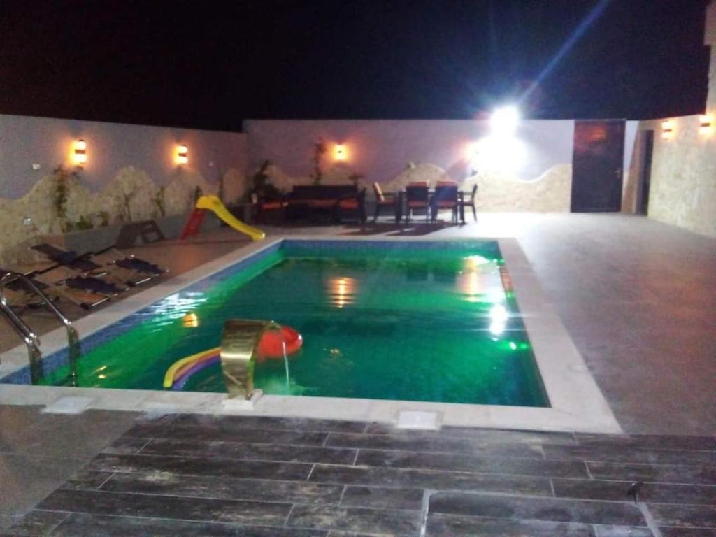 a swimming pool at night with a slide in it at مزرعه الوادي in Al Baḩḩāth