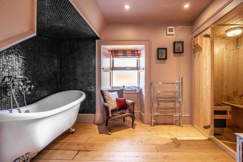 a bathroom with a large tub and a chair at The Millie Luxury Five Star with Sea View in Burghead