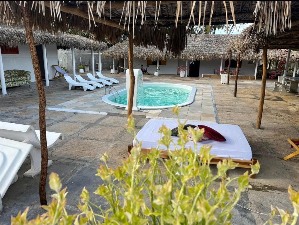 um resort com uma piscina com cadeiras e um guarda-sol em Pousada dunas em Luís Correia