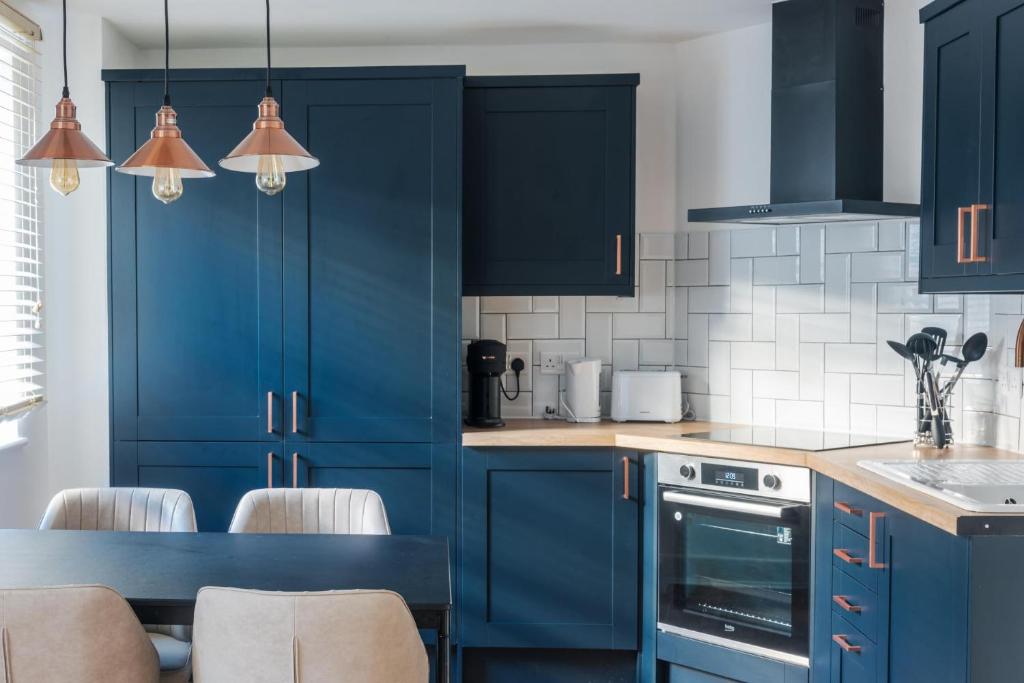 a kitchen with blue cabinets and a table with chairs at Blue Notes in Westbourne Park in London