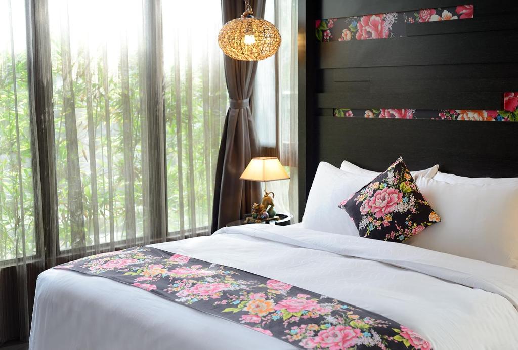 a bedroom with a bed with a floral pillow and a window at Pokara Resort in Jiaoxi