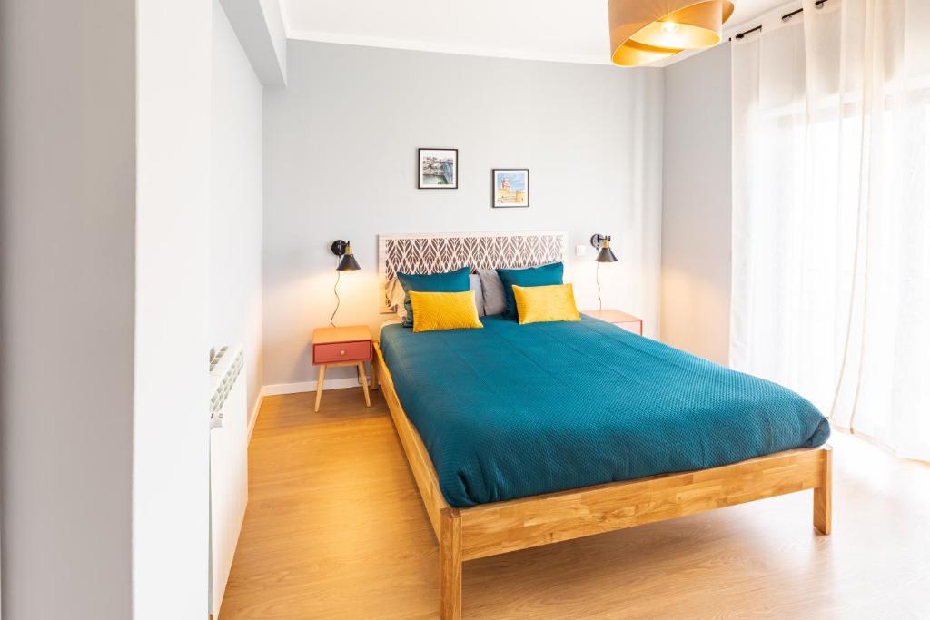 1 dormitorio con 1 cama con sábanas azules y almohadas amarillas en Modern 3 bedrooms 3 bath apartment 5 minutes walk from the Santuary, en Fátima