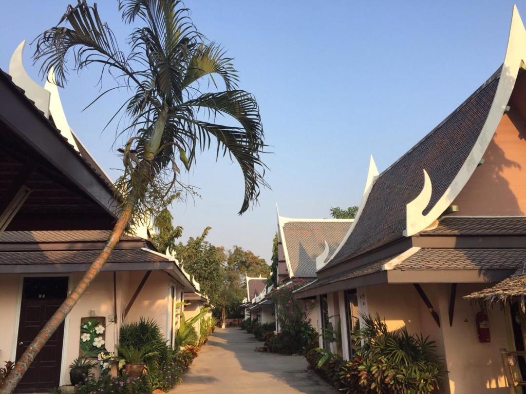 a palm tree is standing next to a building at Sweet Inn Resort in Bang Pahan