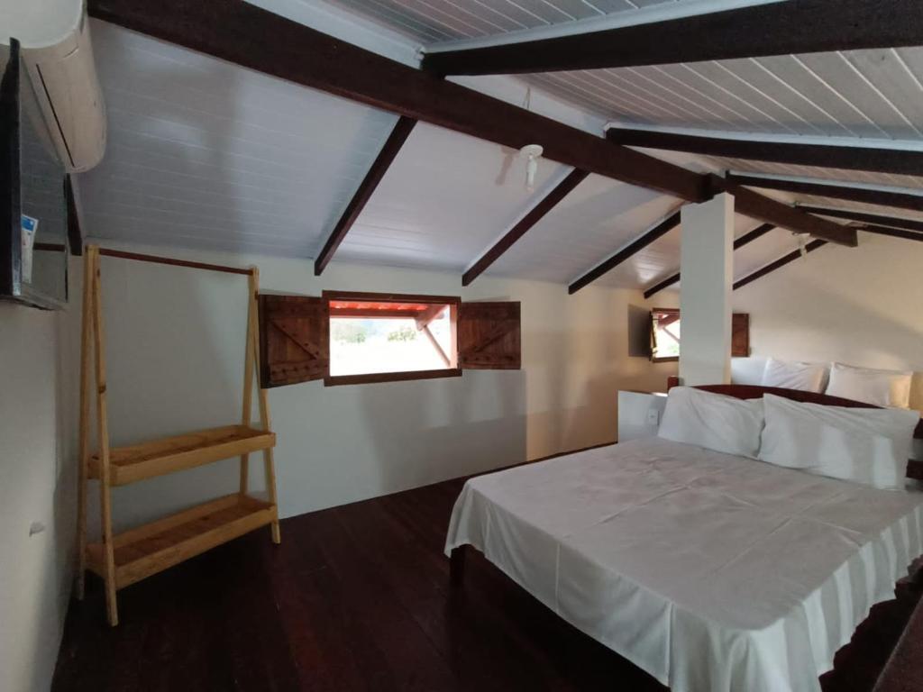 1 dormitorio con 1 cama blanca y 2 ventanas en Chácara Rotha de Piri, en Pirenópolis