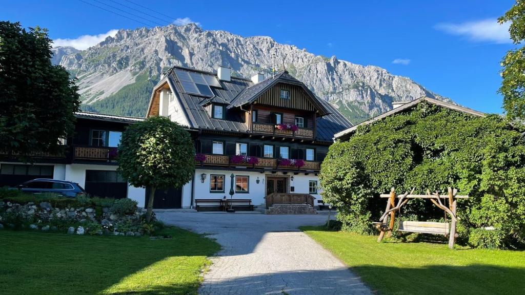 a large house with a mountain in the background at Bauernhof Helpferer in Ramsau am Dachstein