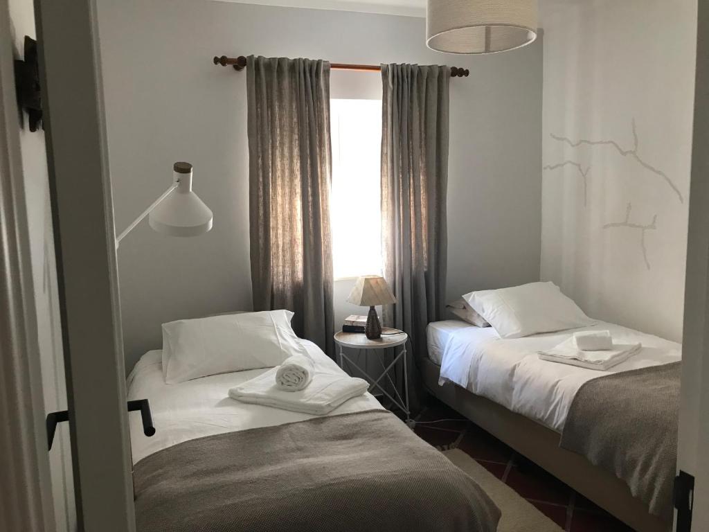 2 Betten in einem kleinen Zimmer mit Fenster in der Unterkunft Casa da Ilha do Baleal in Baleal